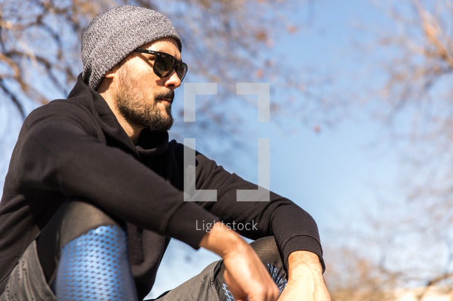 A man in workout clothes sits outdoors.