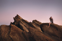 woman sitting on jagged rocks 