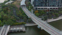 Aerial shot from drone of modern building, urban riverside with palm trees and railway bridge over Saigon River in Ho Chi Minh city
