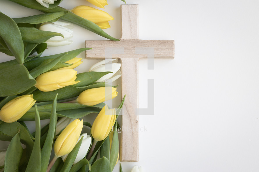 Cross with yellow and white tulips on a white background with copy space