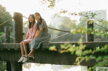 girls sitting on a bridge 