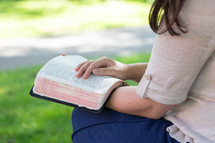 Christian woman sitting outside having quiet time and reading Bible