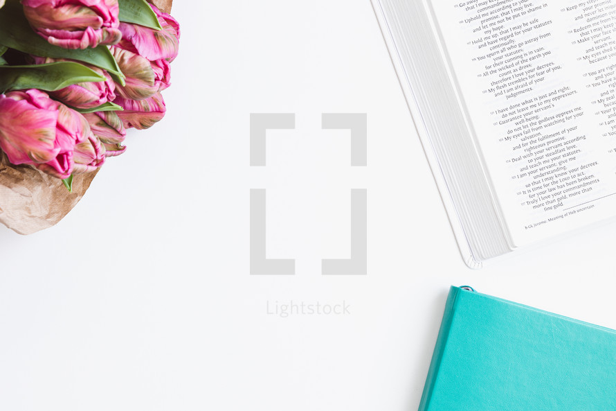 Open bible, teal journal and bouquet of pink tulips on a white background