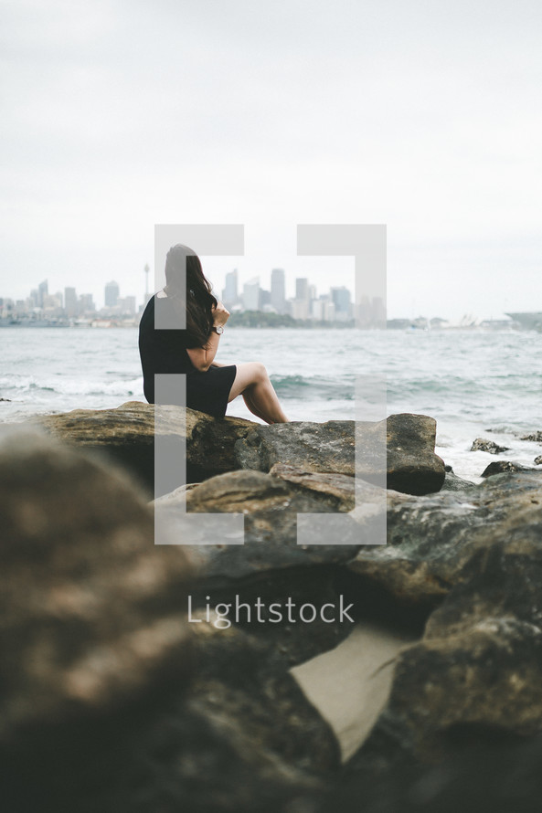 a woman sitting on a rocky shore in Australia 