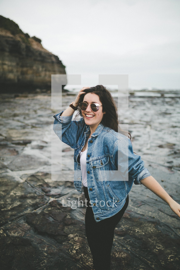 a woman standing on a rocky beach 