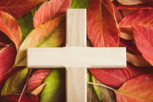 Close up of wood cross on a bed of autumn leaves
