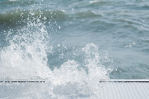 waves splashing onto a metal dock 