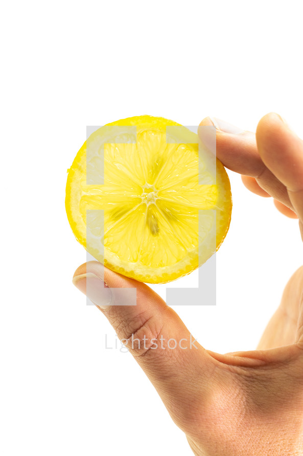 Fingers holding sliced lemon half against a white background 