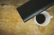 A Bible leaning against a cup of coffee.