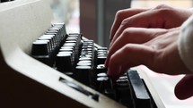Close up of a hand typing on a typewriter. 