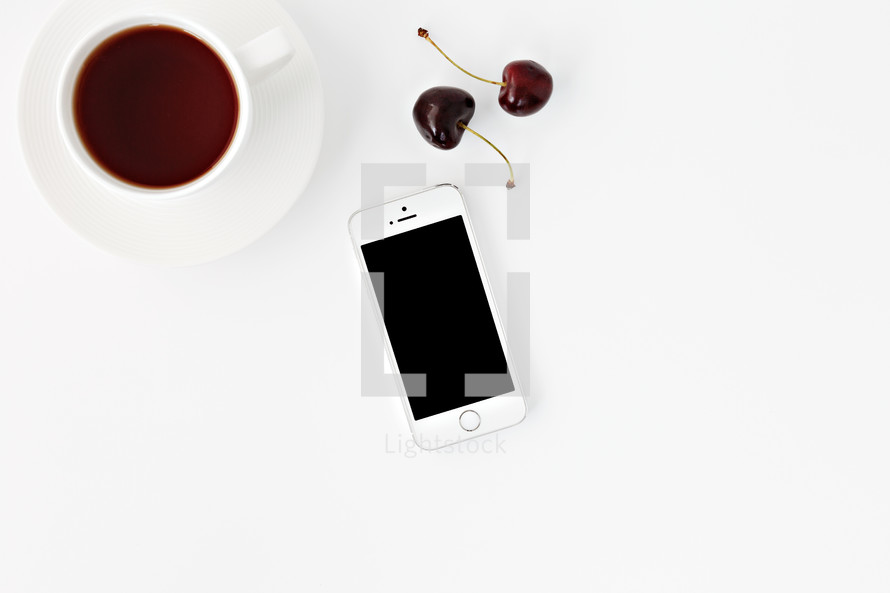 iPhone, cherries, and cup with coffee 