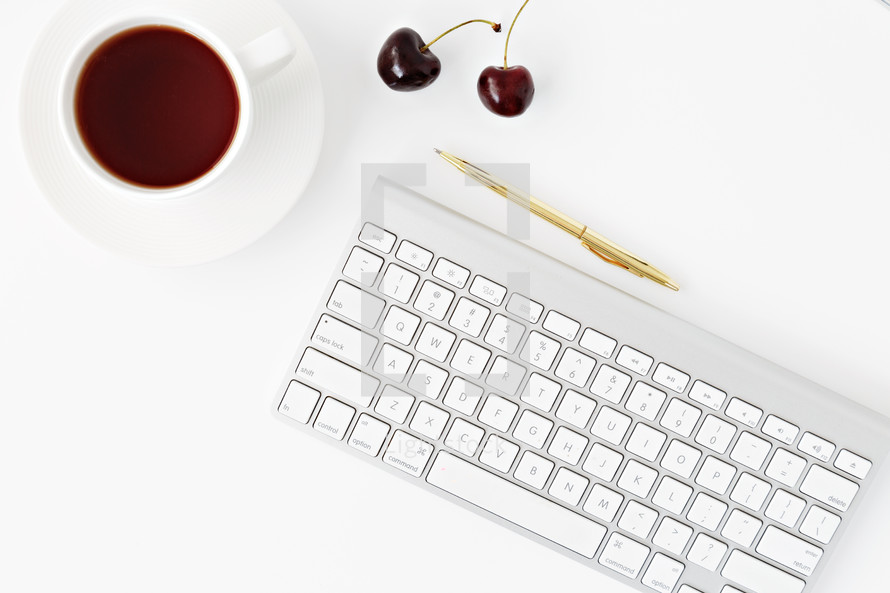 computer keyboard, cherries, gold pen, and cup of coffee 
