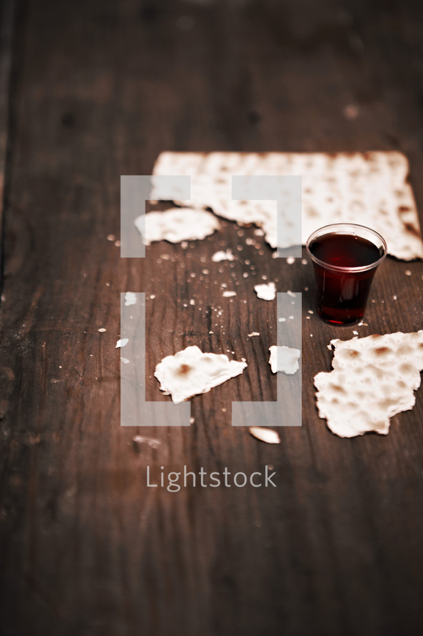 A broken unleavened cracker and communion cup filled with wine