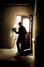 Groom holding the door open for his bride