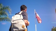 a student looks up at an American flag 
