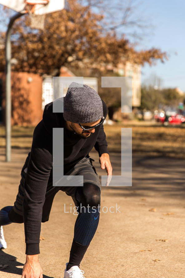A man in workout clothes exercising in a park.
