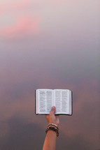 a hand holding a Bible in the air