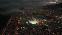 Nighttime drone shot over Quito shows lit up Atahualpa Olympic Stadium	
