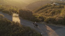 A man rides a horse on the street during sunset