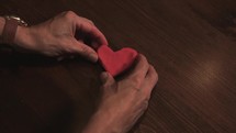 man molding a heart of clay 