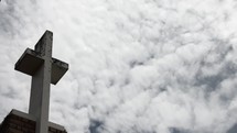 clouds moving over a cross on the roof of a church 