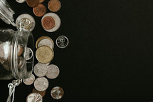 Coins coming out of jar on a black background