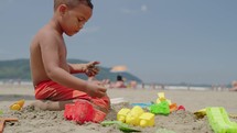 Kid playing sand with toy at the beach on summer vacation. Little child boy enjoy and have  fun outdoor activity playing.
