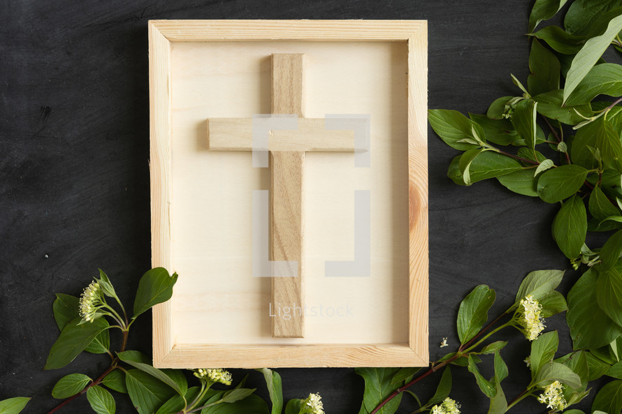 wood cross on chalkboard with border of green leaves