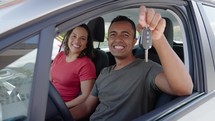 Young hispanic couple smiling confident holding key of new car at street
