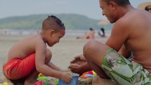 Father and son making sand castle at tropical beach. Child with dad outdoor at seaside playing together