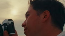 The man is taking pictures and in the foreground is the sunset
