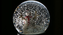 snow falling in a snow globe on a snowman 