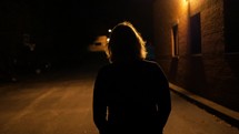 a woman walking outdoors alone at night 