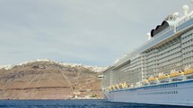 Luxuary Giant cruise ship docked in Santorini bay in greece under sunny day vacation holiday time.