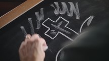 cross being drawn on chalkboard