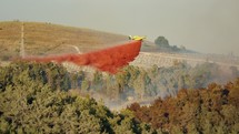 Fire fighter plane drops fire retardant on a forest fire in the hills