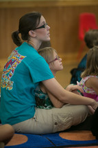 child sitting in her mother's lap during a children's ministry