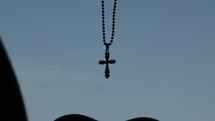 Christian man driving in car with a cross necklace, rosary hanging in windshield on a busy highway with rush hour traffic in city of Dubai in the united Arab emirates.