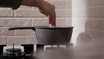 Female Hand Pouring Salt In Cooking Pan - Close Up