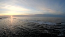 Aerial static drone shot of waves of Langeoog Island, Germany at the sunset.