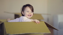 happy child playing in a cardboard box 