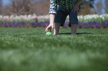 Young boy gathering Easter eggs in a flower garden