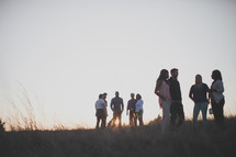 groups of people standing around talking outdoors in a field 