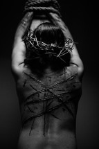 The suffering of Christ -- a beaten Jesus in His crown of thorns bound to the cross with rope.