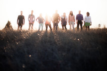 group of people in a row standing outdoors in sunlight 