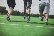 men running on a football field 