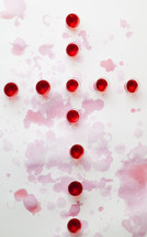 spilled red wine in communion cups in the shape of a cross