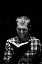 man reading a Bible with a smile on his face 