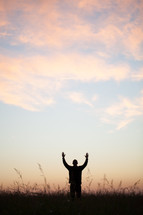 silhouette of a man with his hands raised in worship to God