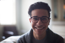 smiling young man in reading glasses 